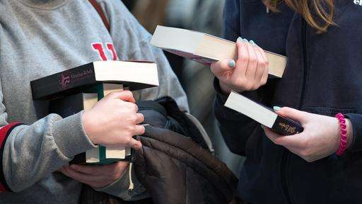 Besucherinnen der Leipziger Buchmesse betrachten Bücher an einem Verlagsstand.