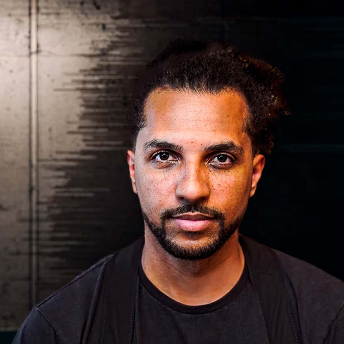 Host des Podcast Deutschrap Ideal Simon Vogt steht vor einer Wand und blickt in die Kamera.