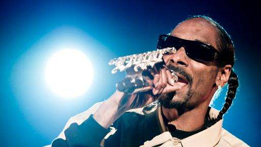 Snoop Dogg sing in ein Mikrofon an dem glitzern sein Schriftzug prangt.