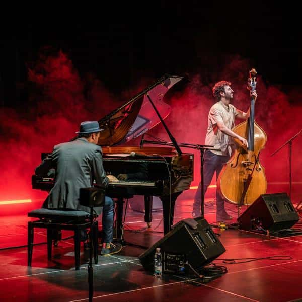 Drei Musiker treten auf einer Bühne mit rotem Licht auf.