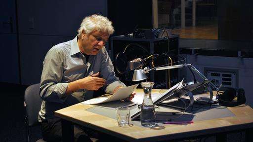 Schauspieler und Erzähler der Hörbiografie berühmter Komponist:innen: Udo Wachtveitl, mit weißen Haaren, blauem Hemd im Aufnahmestudio.