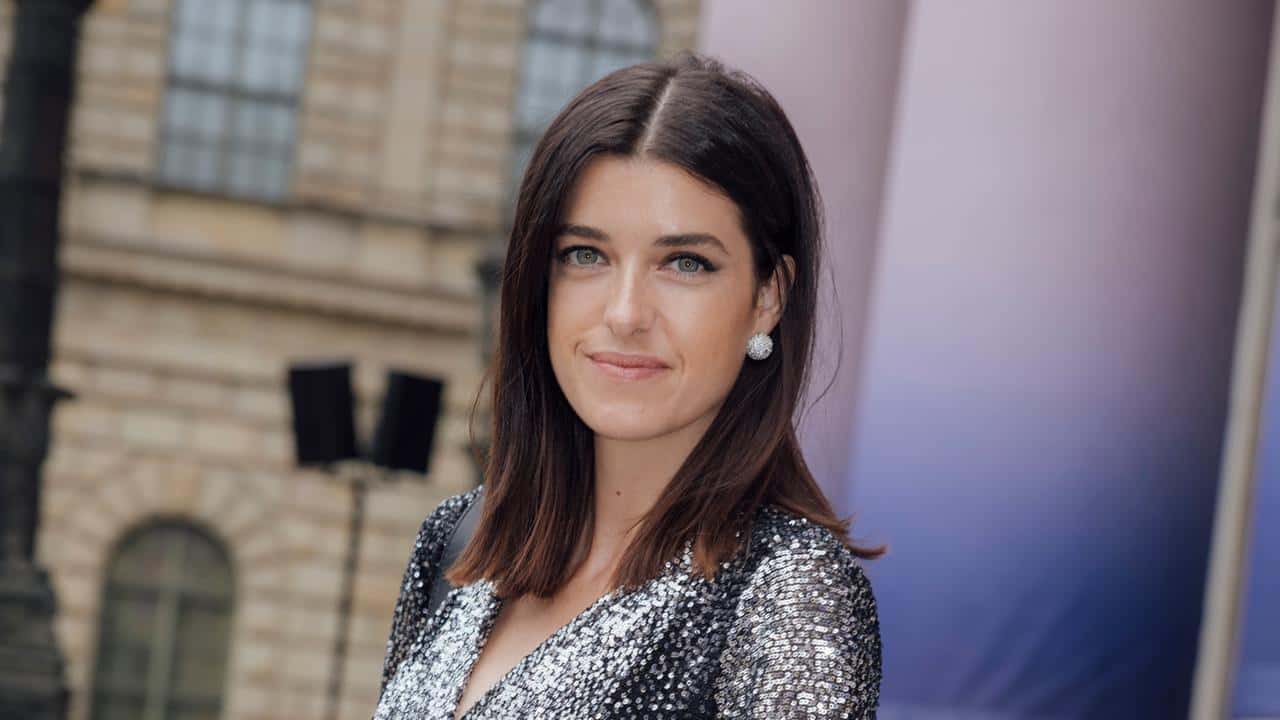 Schauspielerin Marie Nasemann im anthrazitfarben Paillettenkleid vor einer Treppe.