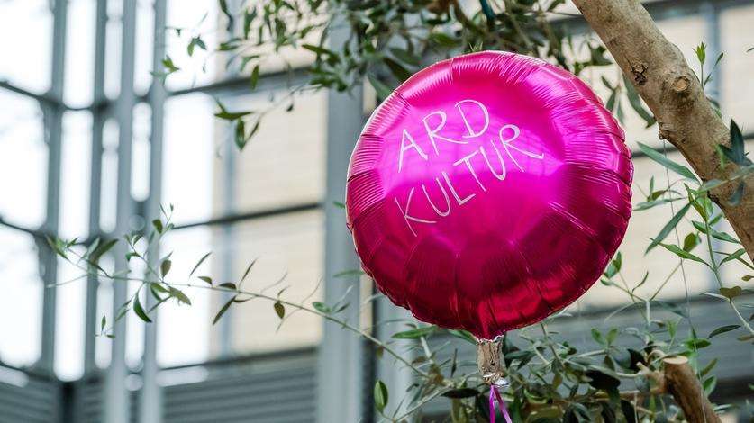 Ein pinker Luftballon mit der Aufschrift ARD Kultur schwebt in der Luft.