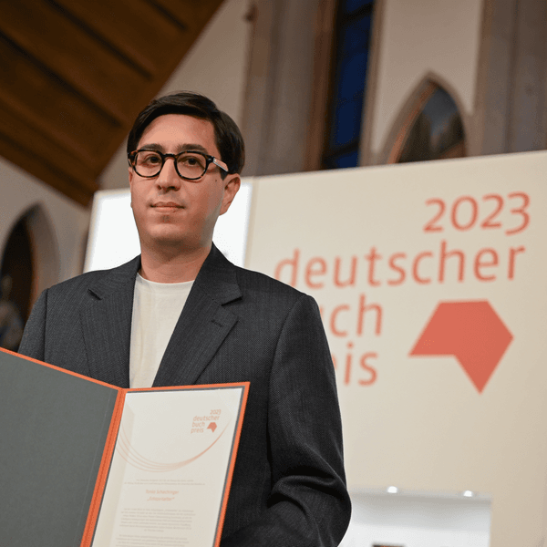 Der österreichische Autor Tonio Schachinger hält nach der Auszeichnung mit dem Deutschen Buchpreis 2023 für seinen Roman „Endzeitalter“ die Urkunde.