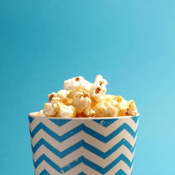 Ein Becher mit Popcorn auf blauem Hintergrund.