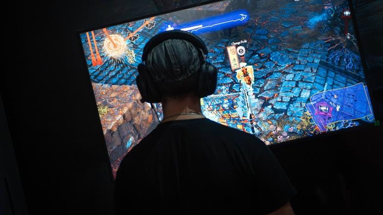 Eine Person sitzt vor einem großen Bildschirm und spielt ein Videospiel.