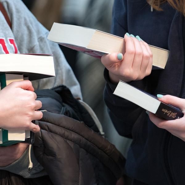 Besucherinnen der Leipziger Buchmesse betrachten Bücher an einem Verlagsstand.