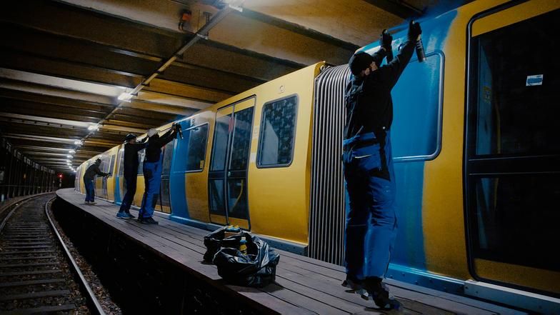Graffitykünstler sprayen einen Zug in einem U-Bahn Schacht