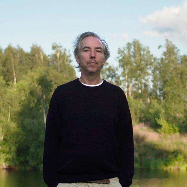Olli Schulz steht am grasbewachsenen Ufer eines Teichs.