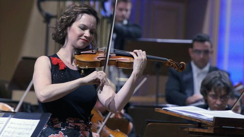 Violinistin Hilary Hahn, mittellange, braune Haare spielt zusammen mit einem Orchester.