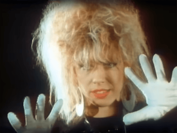 Still eines 80er-Jahre Musikvideos mit einer Frau mit Handschuhen, die in die Kamera gestikuliert