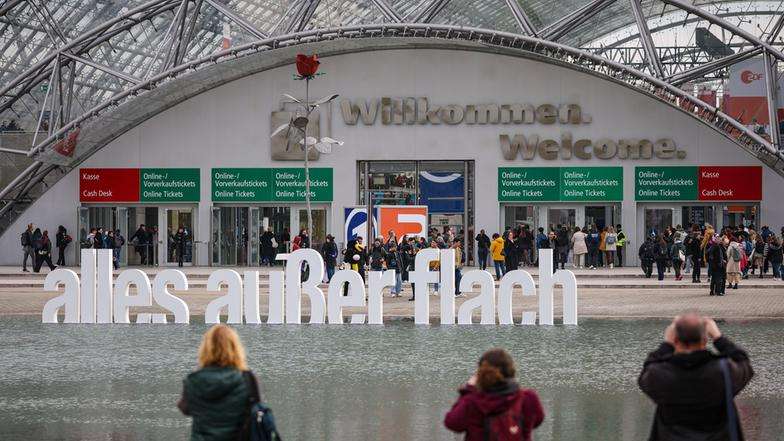Besucher fotografieren den Schriftzug „alles außer flach“ vor der Leipziger Buchmesse.