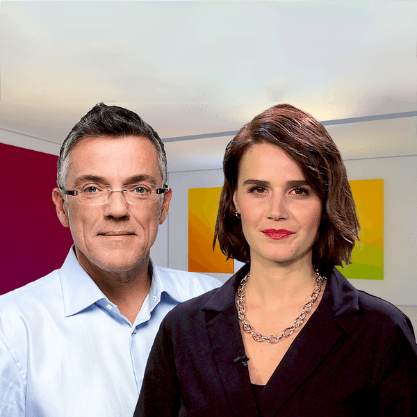 Mann mit randloser Brille und eine Frau im dunklen Kostüm vor Wand mit farbigen Quadraten. Die artour-Moderatoren Yara Hoffmann und Thomas Bille in einem Ausstellungsraum.